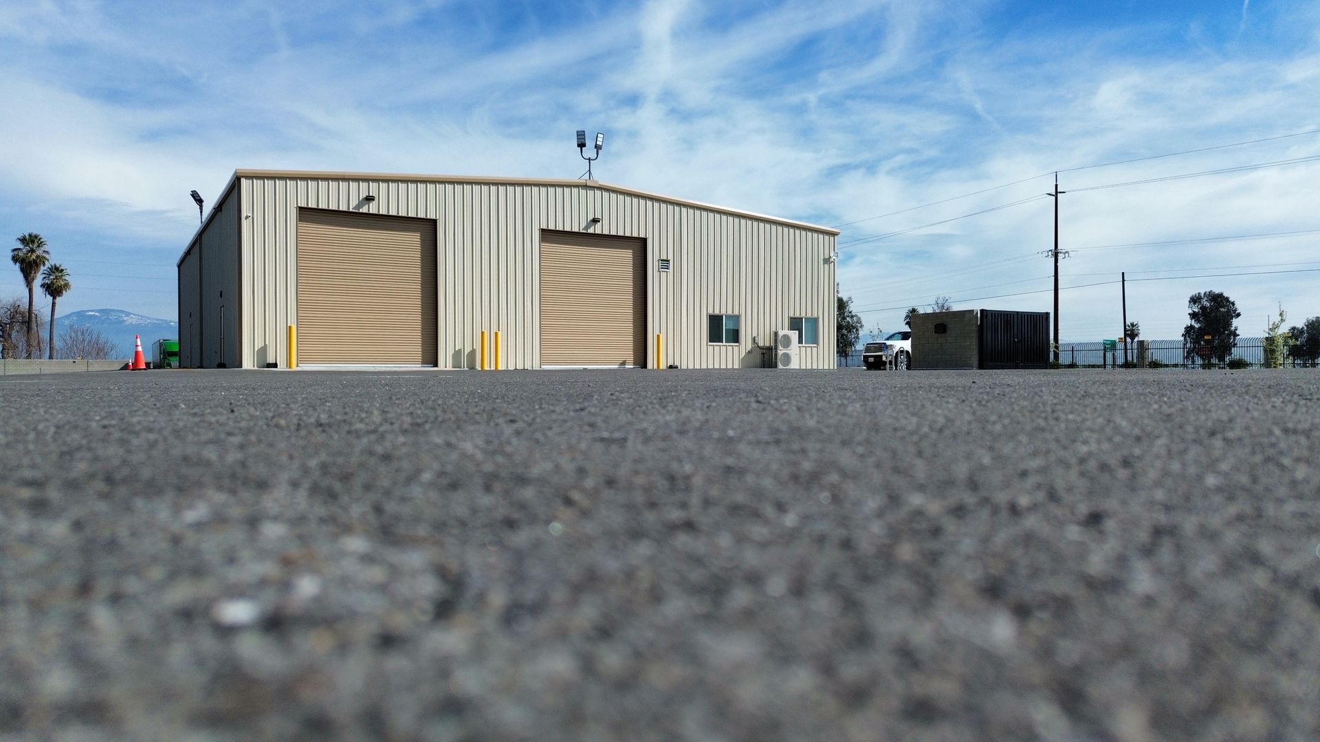 a large metal building with two garage doors is sitting in the middle of a parking lot .