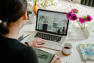 A woman is sitting at a table using a laptop computer.