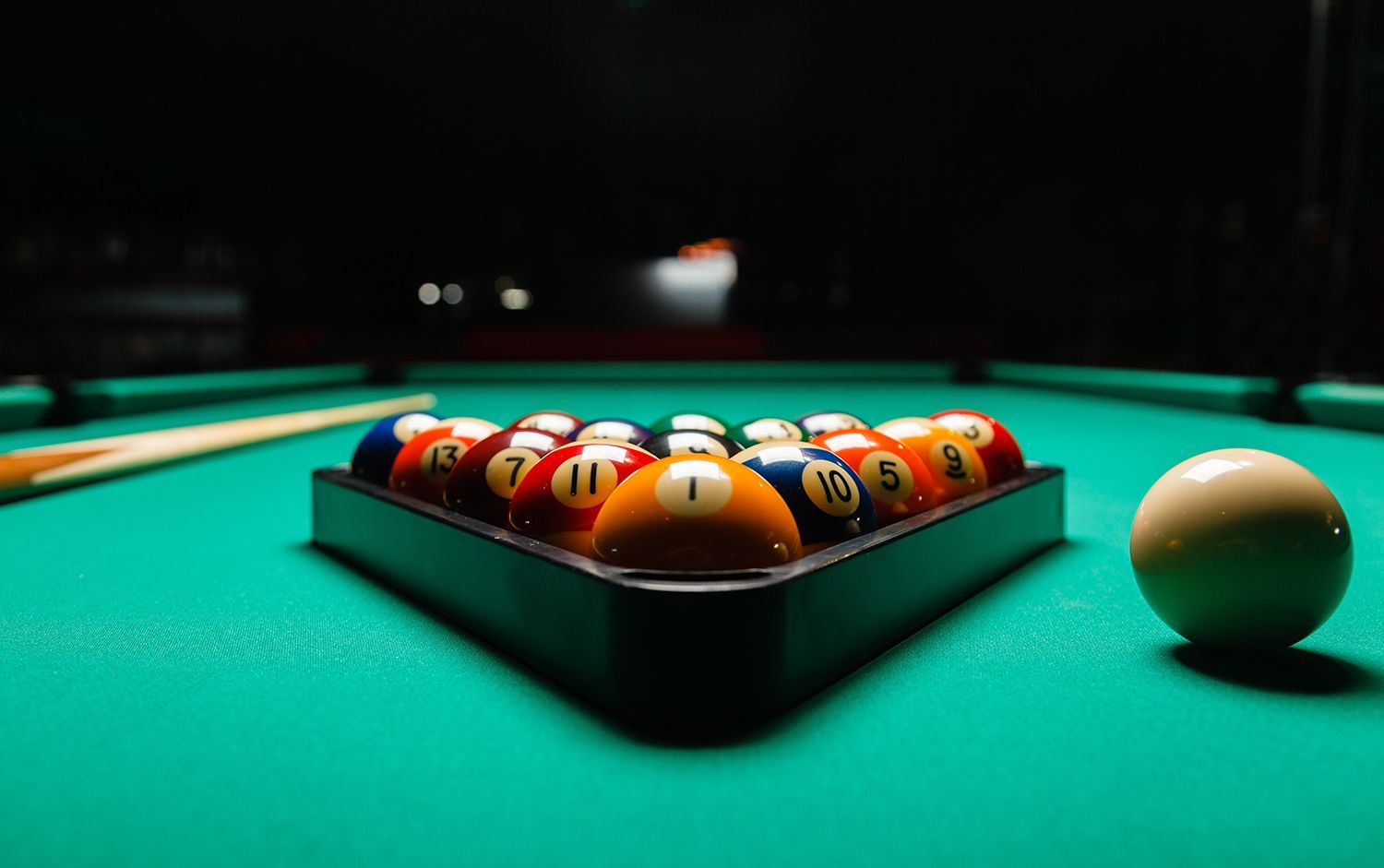 A rack of billiard balls arranged in a triangle on a green pool table