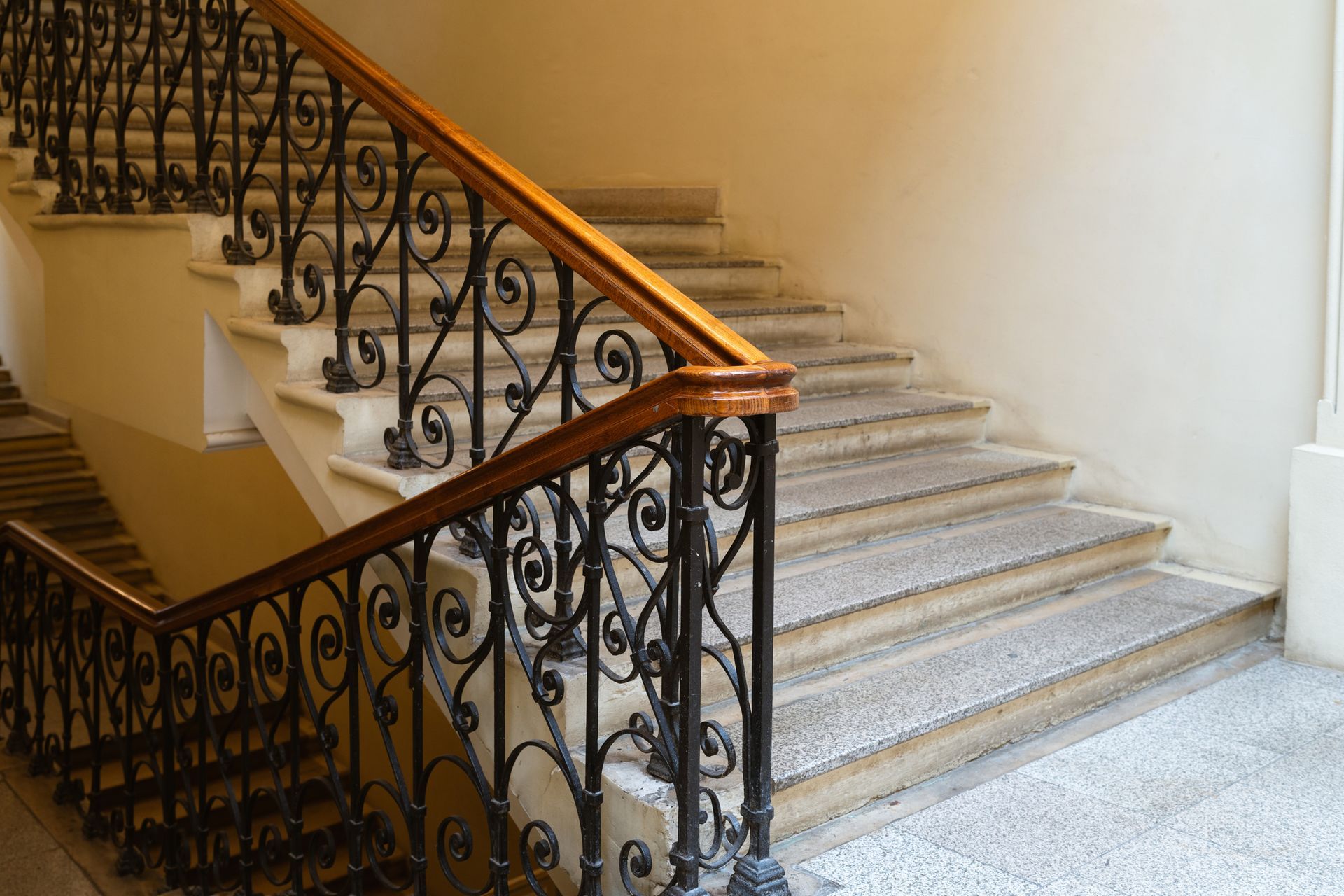Elegant staircase with ornate black iron railing and wooden handrail.