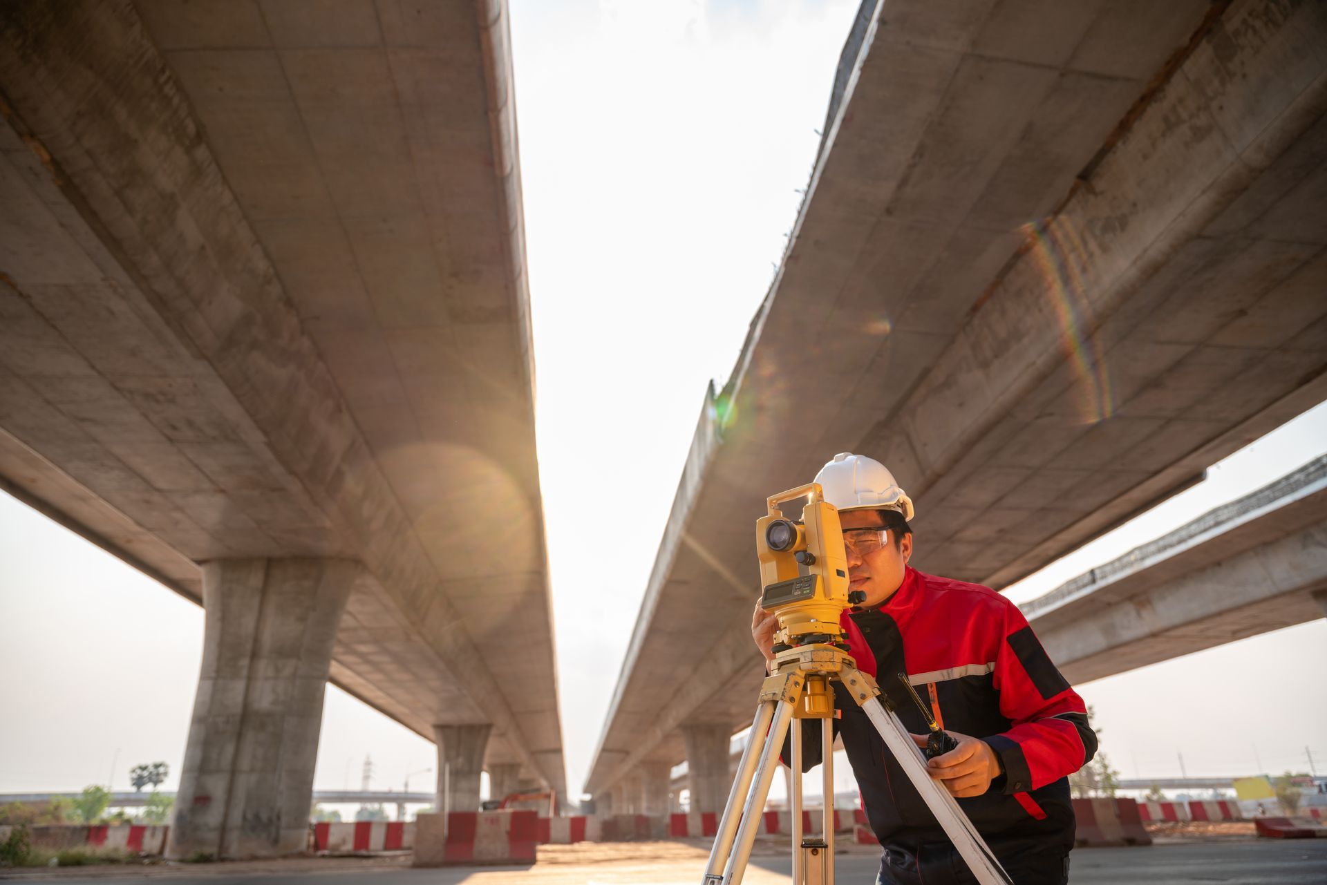 A man is using a total station to measure the height of a bridge.