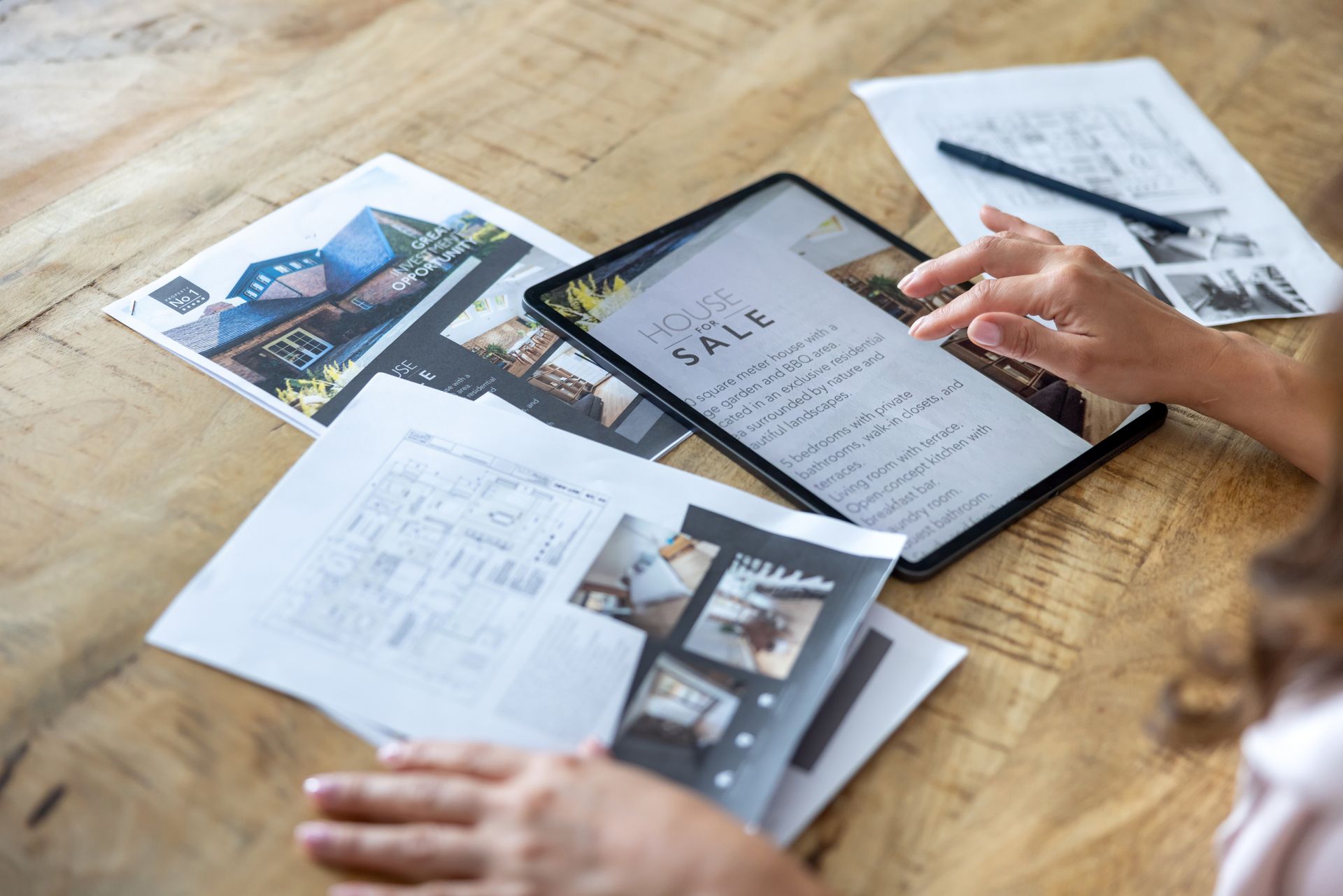 A woman is sitting at a table looking at a tablet.