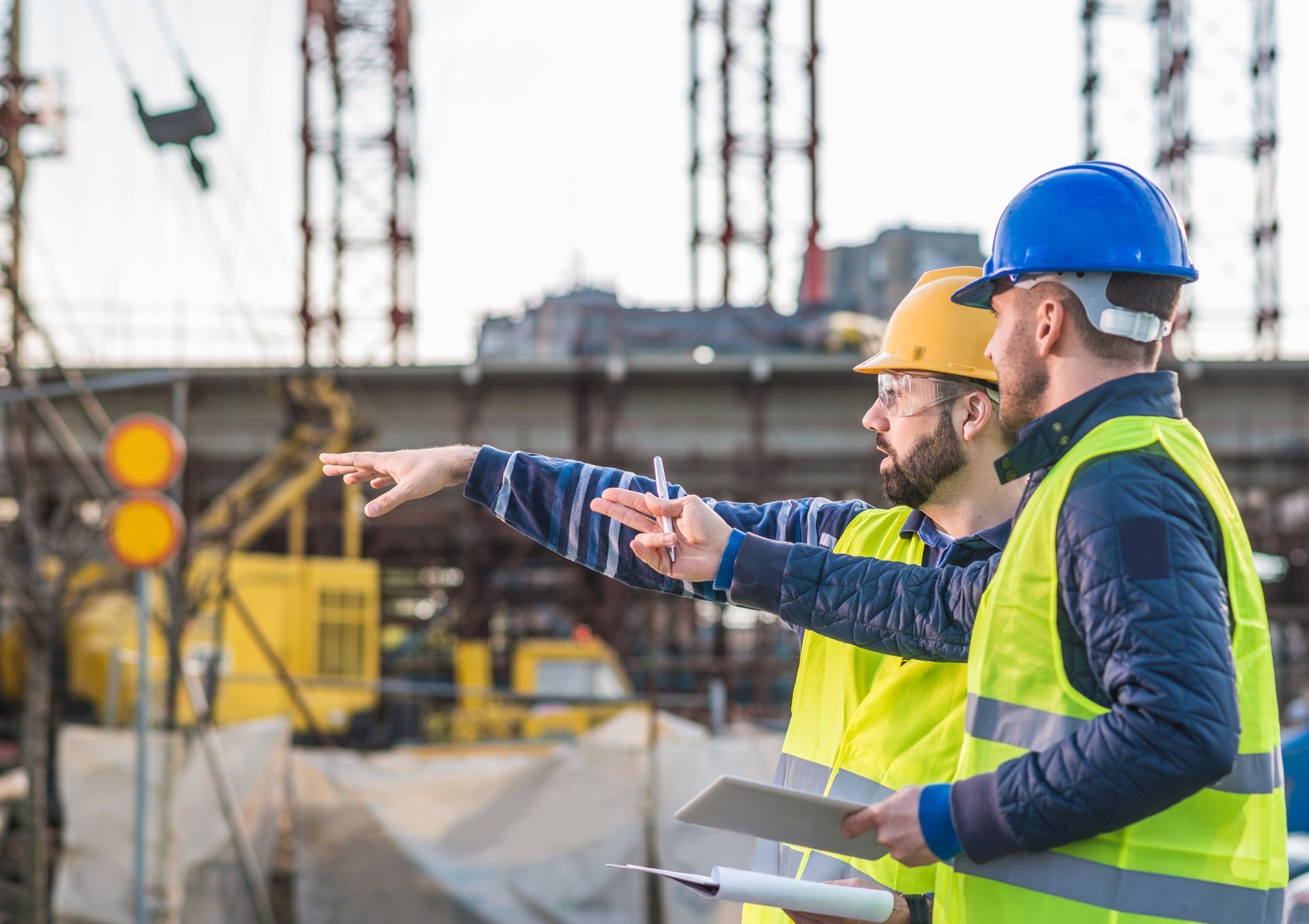 Two construction workers are standing next to each other on a construction site.