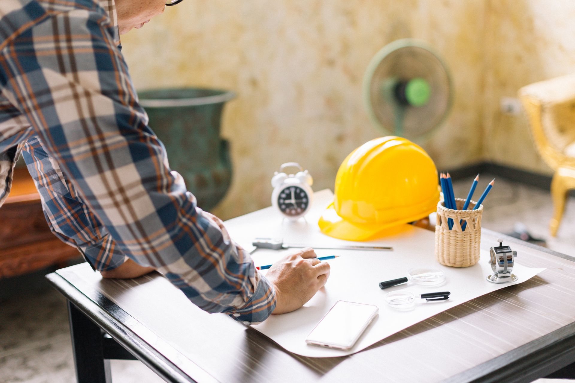 A man is sitting at a table drawing on a piece of paper.