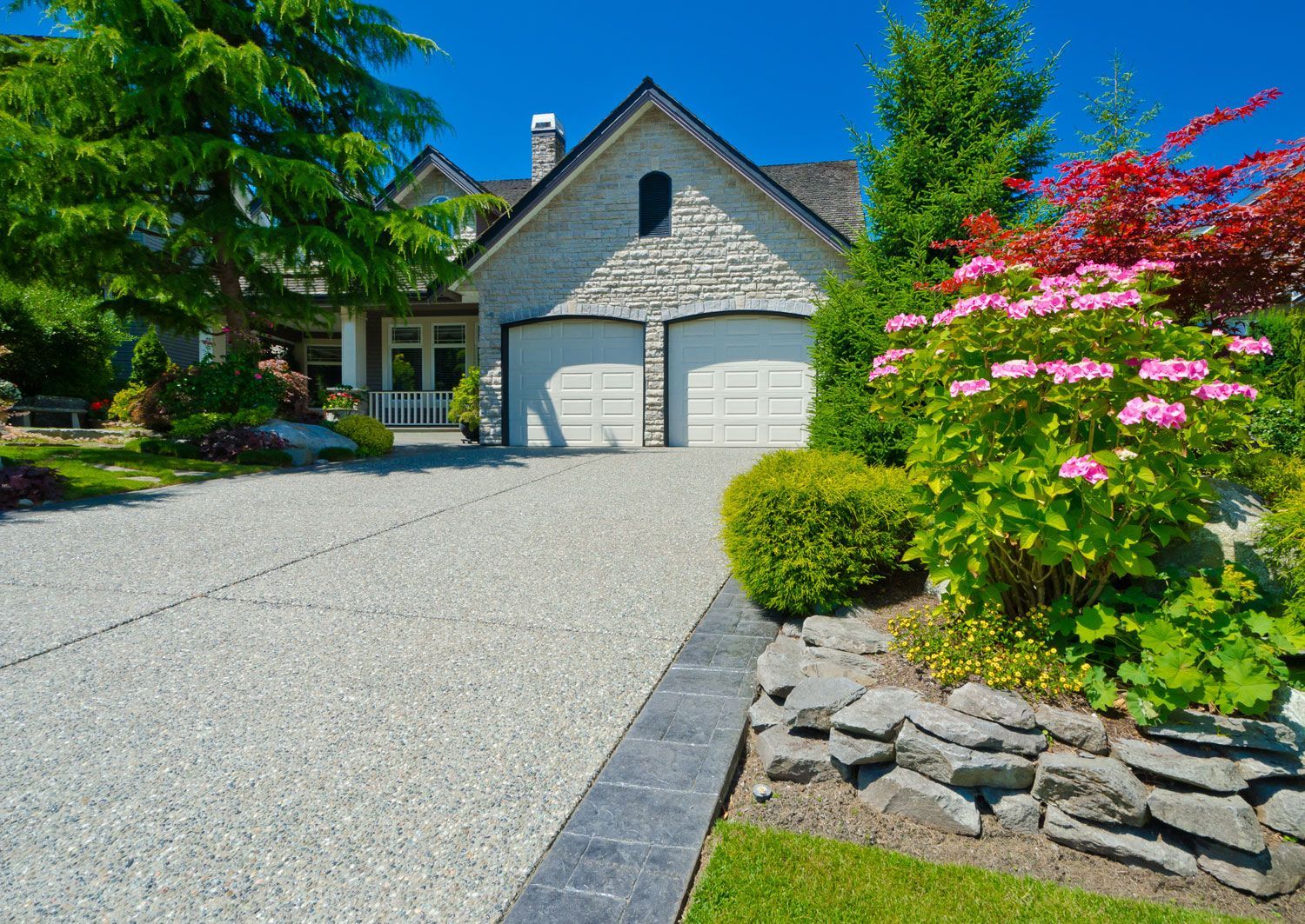 Double doors garage with wide and long driveway with nicely trimmed and landscaped front yard