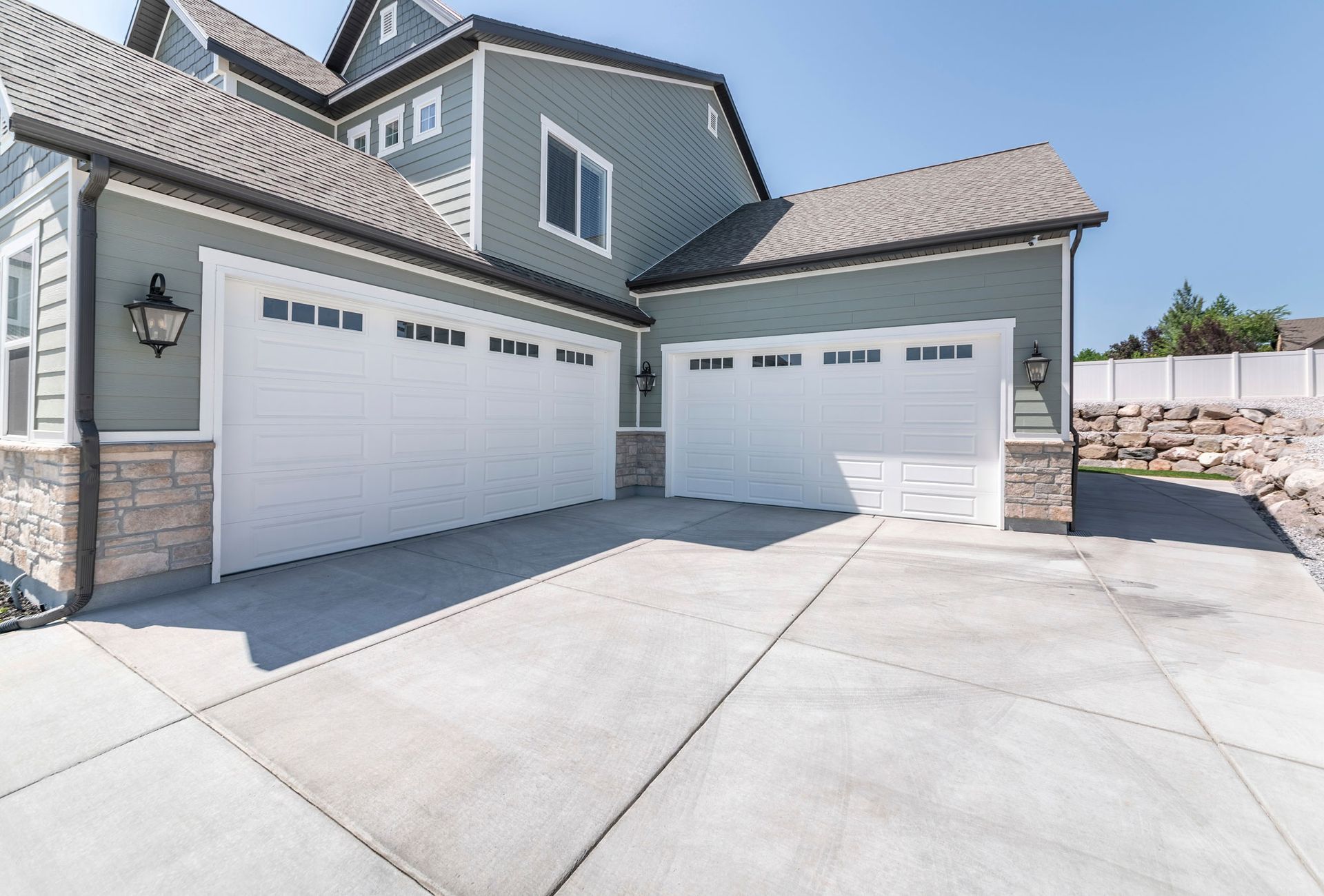 Exterior of a house with concrete driveway and two closed white garage doors with windows