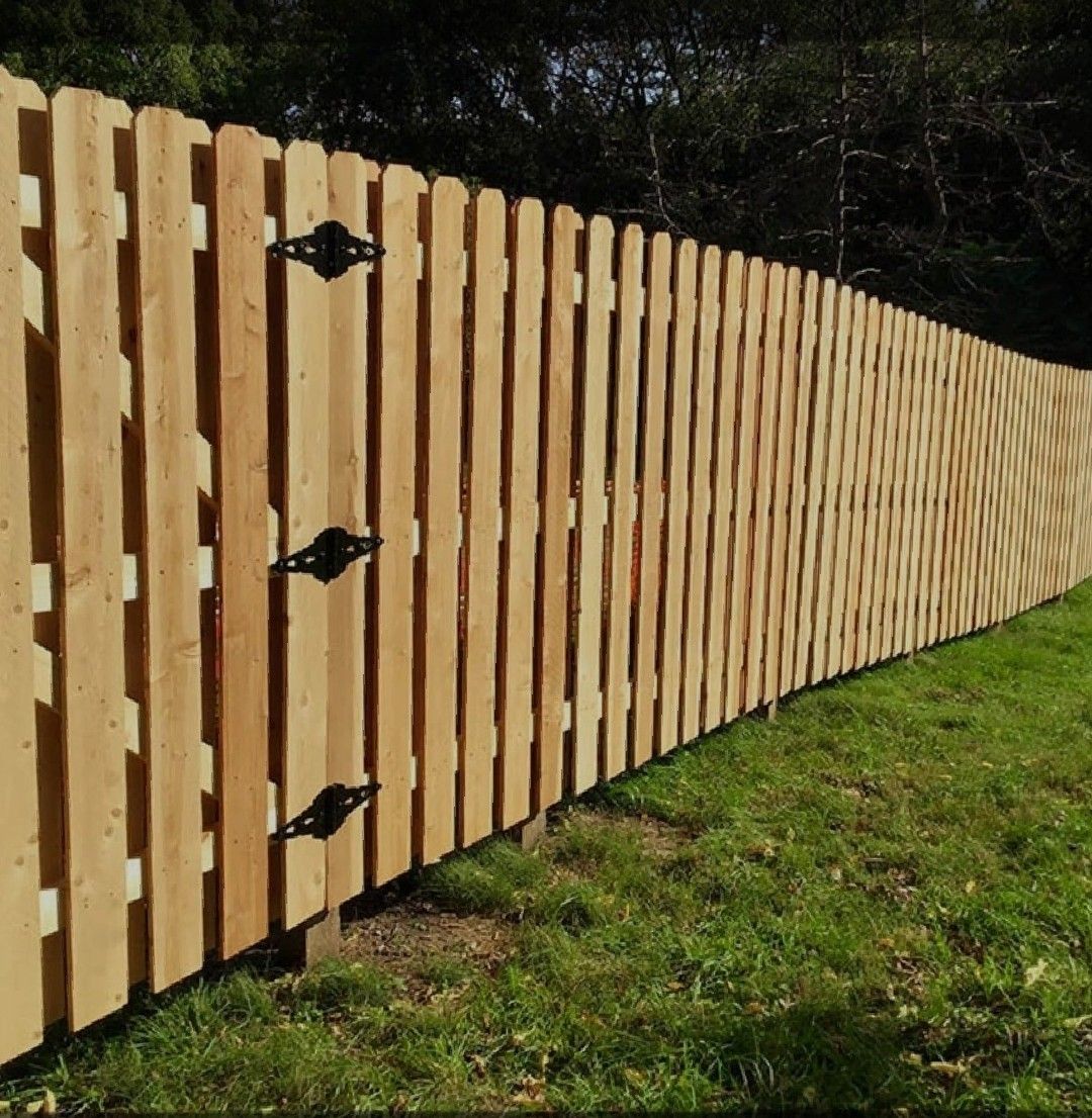 A long wooden fence surrounds a lush green field