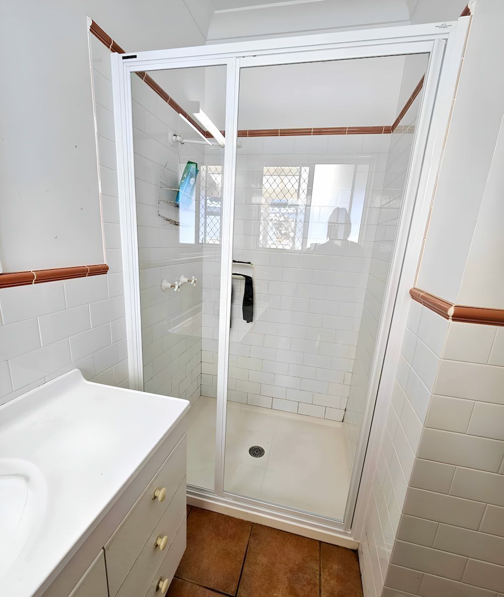 A Bathroom With A Sliding Glass Shower Door And A Sink — Mobile Shower Door Doctor In Mountain Creek, QLD