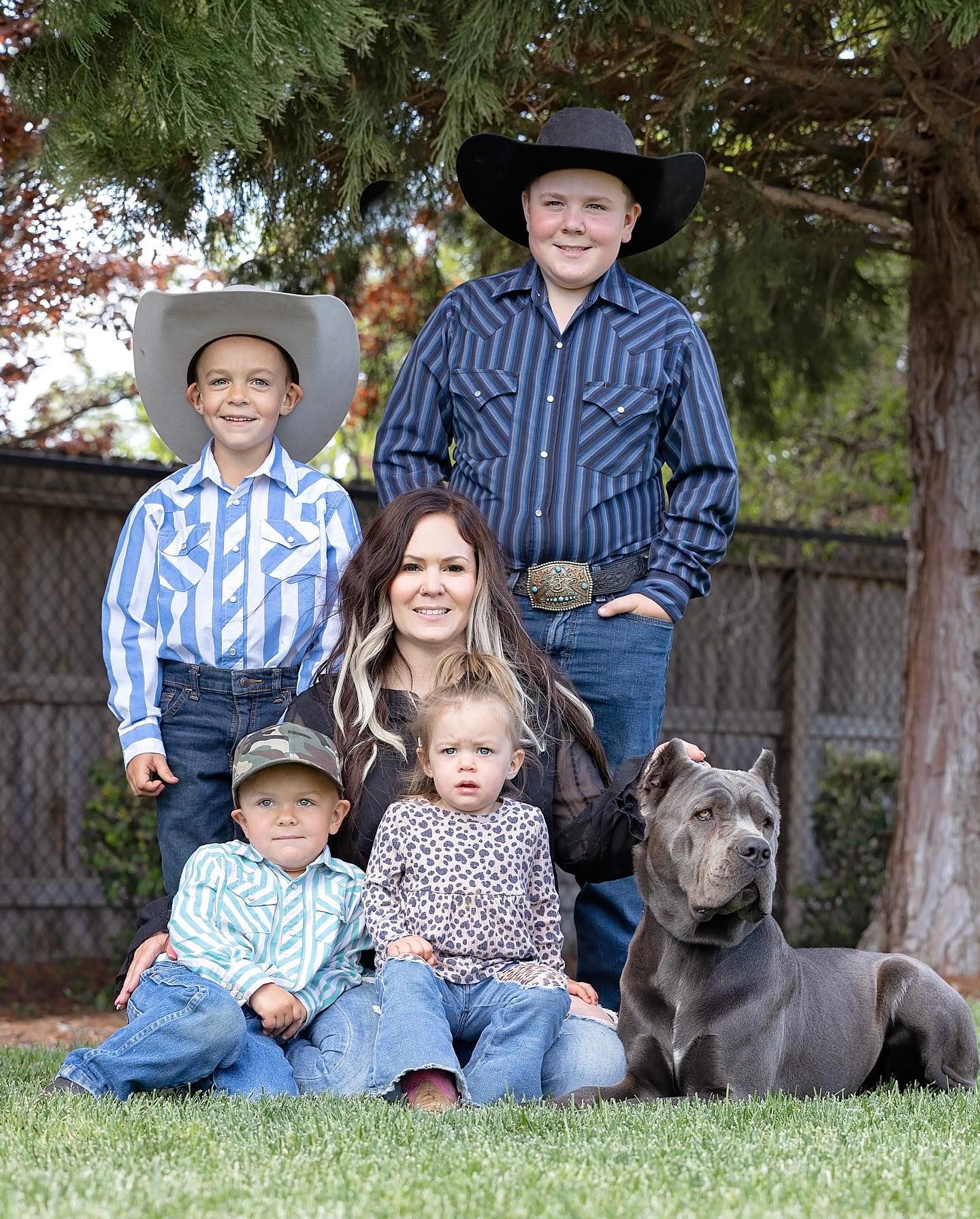 A family posing for a picture with a dog in the grass.