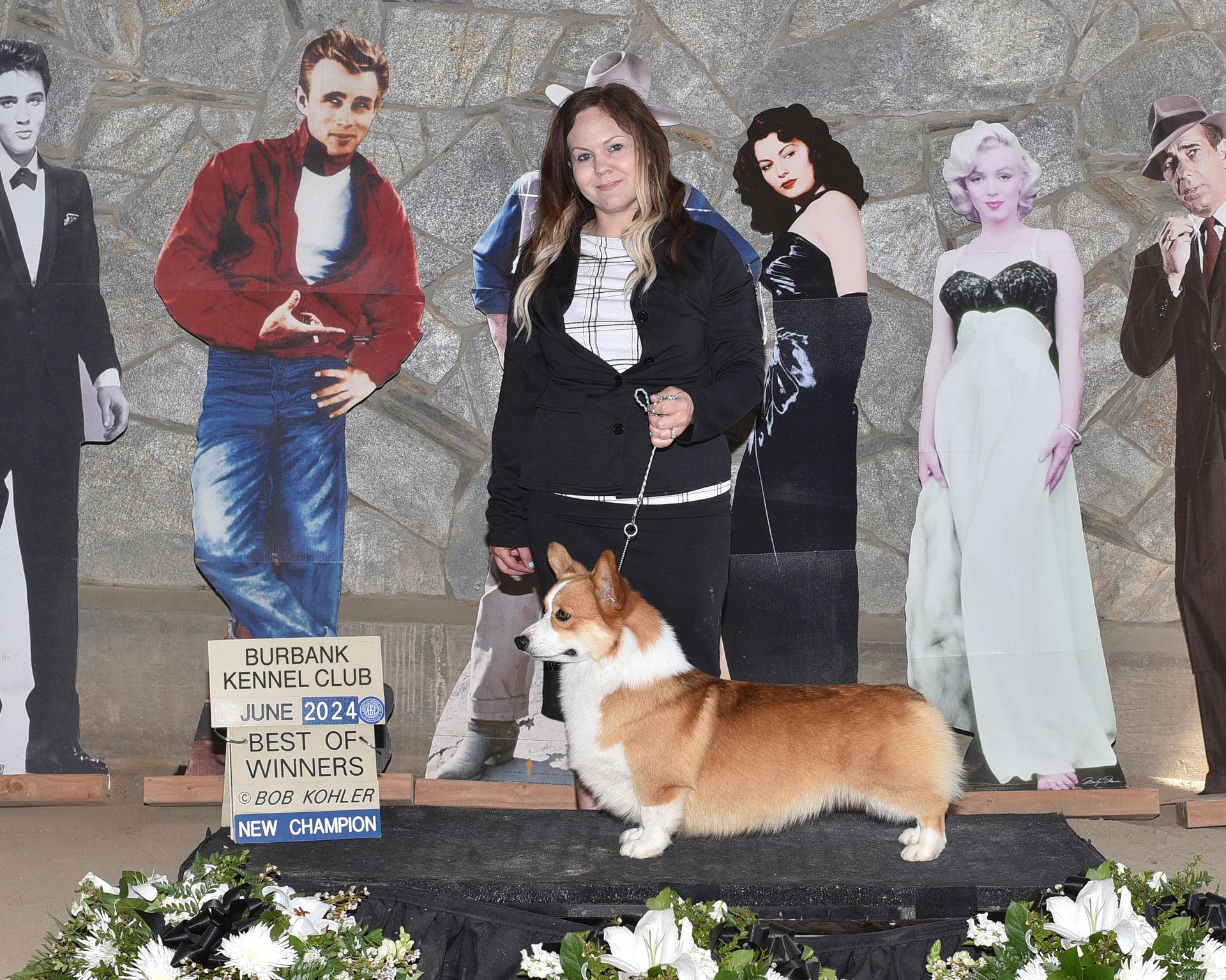 A woman and a dog are posing for a picture in front of cardboard cutouts of elvis presley and marilyn monroe