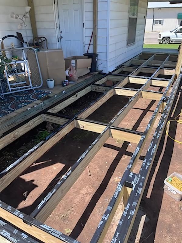 Wooden deck frame under construction outside a white house.