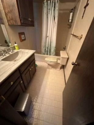 Bathroom with dark wood vanity, white fixtures, and patterned shower curtain.