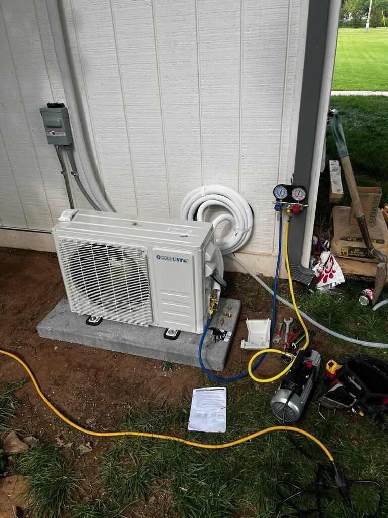 HVAC unit installation outdoors. Gray unit on concrete, tools, gauges, tubing and electrical connections.