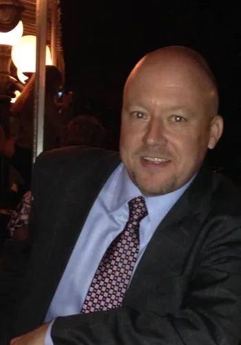 A man in a suit and tie is smiling for the camera