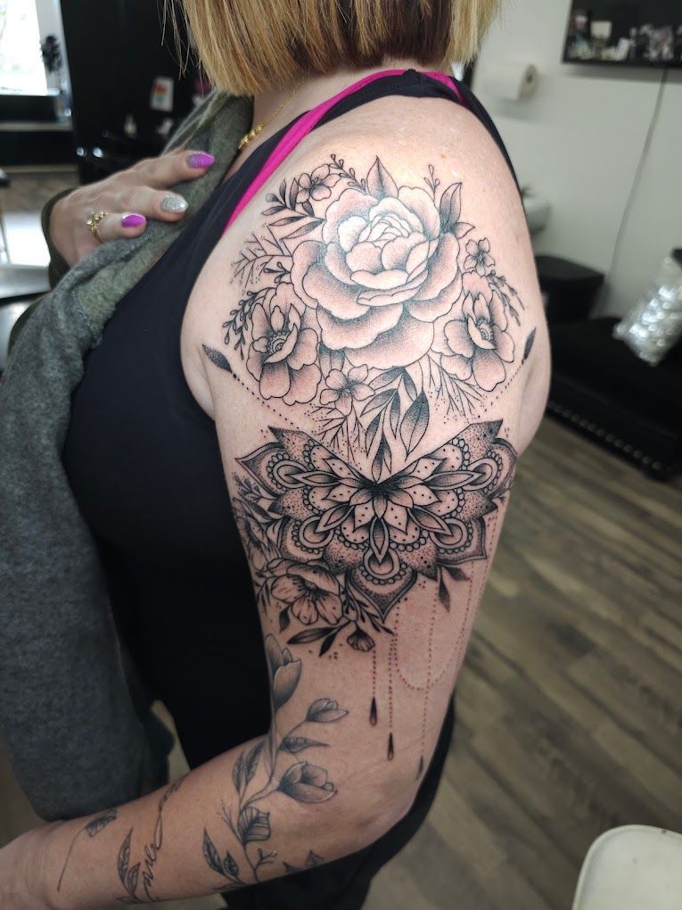 A woman has a tattoo of a rose and a mandala on her arm.