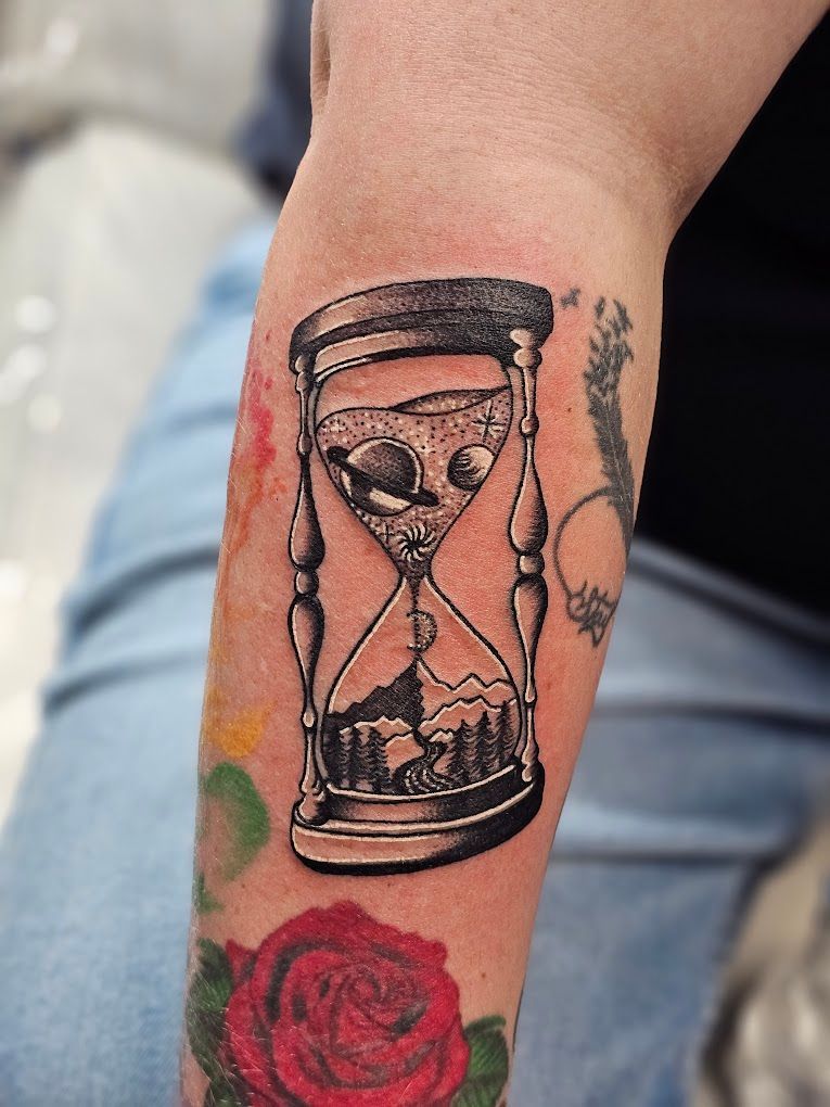 A person has a tattoo of an hourglass on their arm.