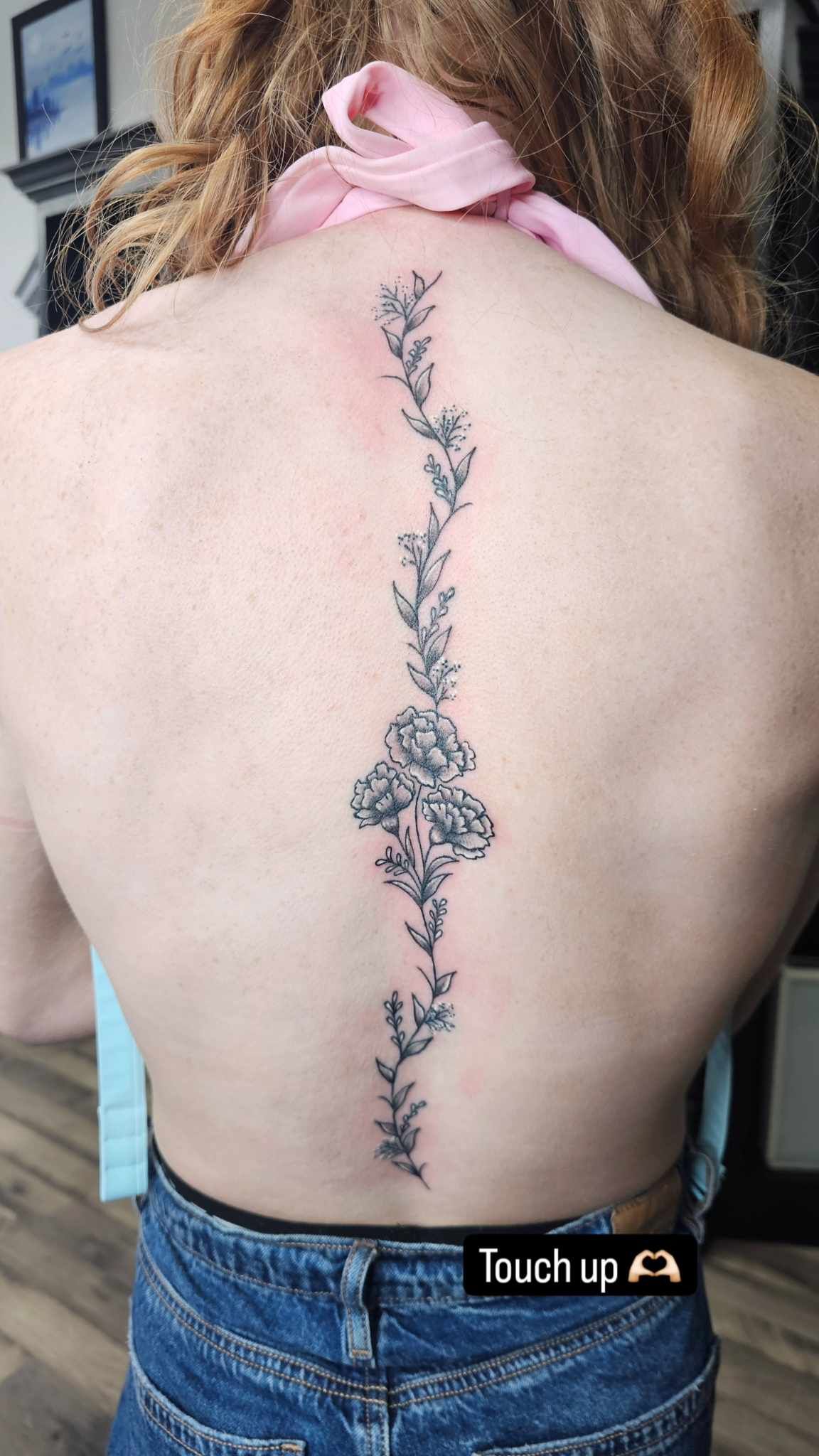 A woman with dreadlocks has a tattoo on her back.