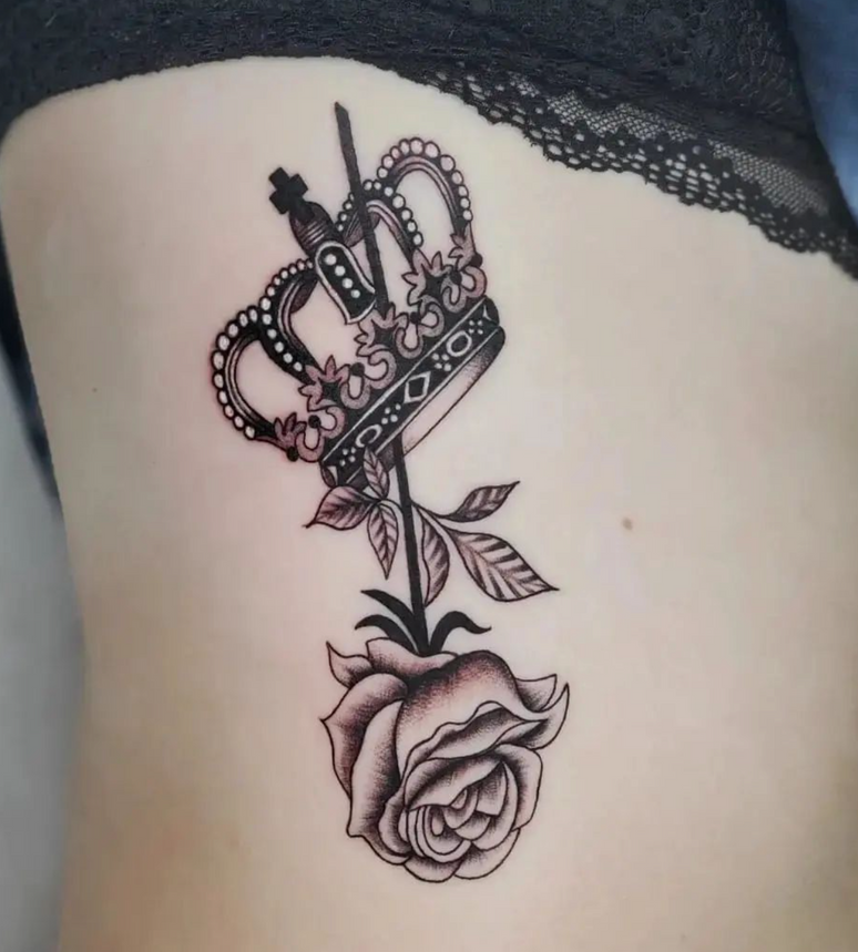 A black and white tattoo of a crown and a rose