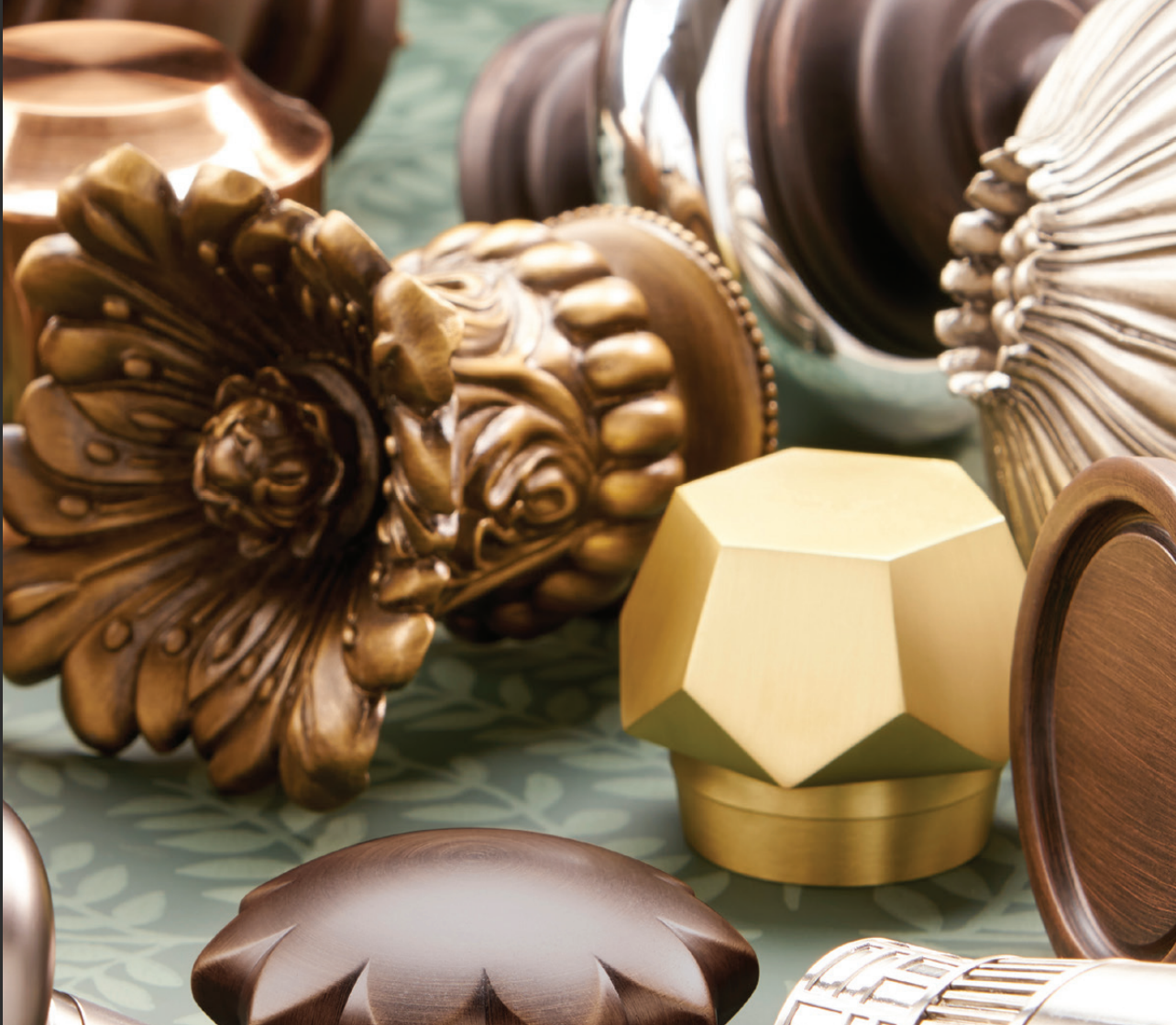 Close-up of various decorative curtain rod finials in bronze, gold, and silver tones.