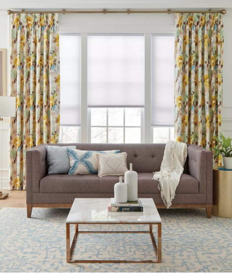 Living room with mauve sofa, floral curtains, white blinds, and marble coffee table.