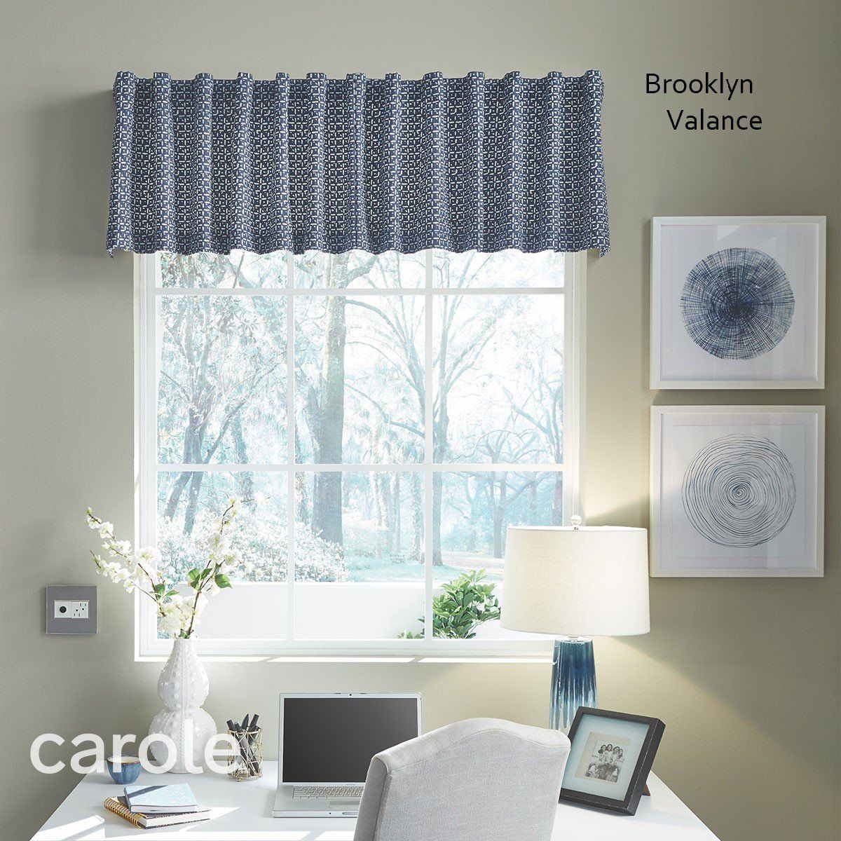 Window with blue-patterned valance, desk, art, and a snowy view.