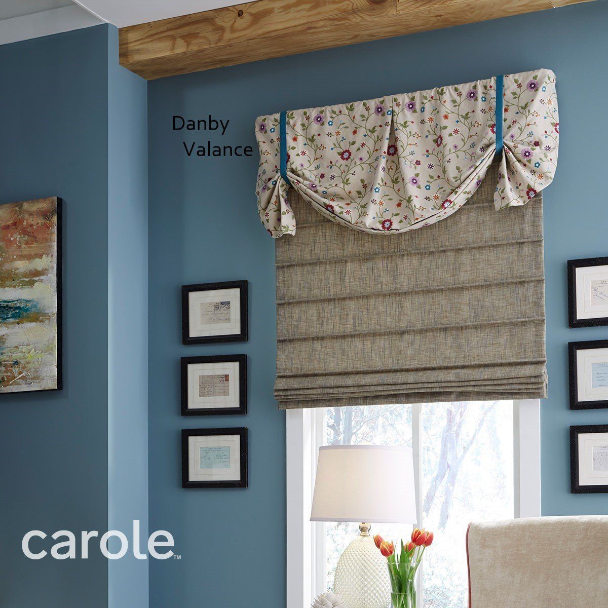 Blue wall with Danby valance and tan Roman shade, framed art, and lamp.
