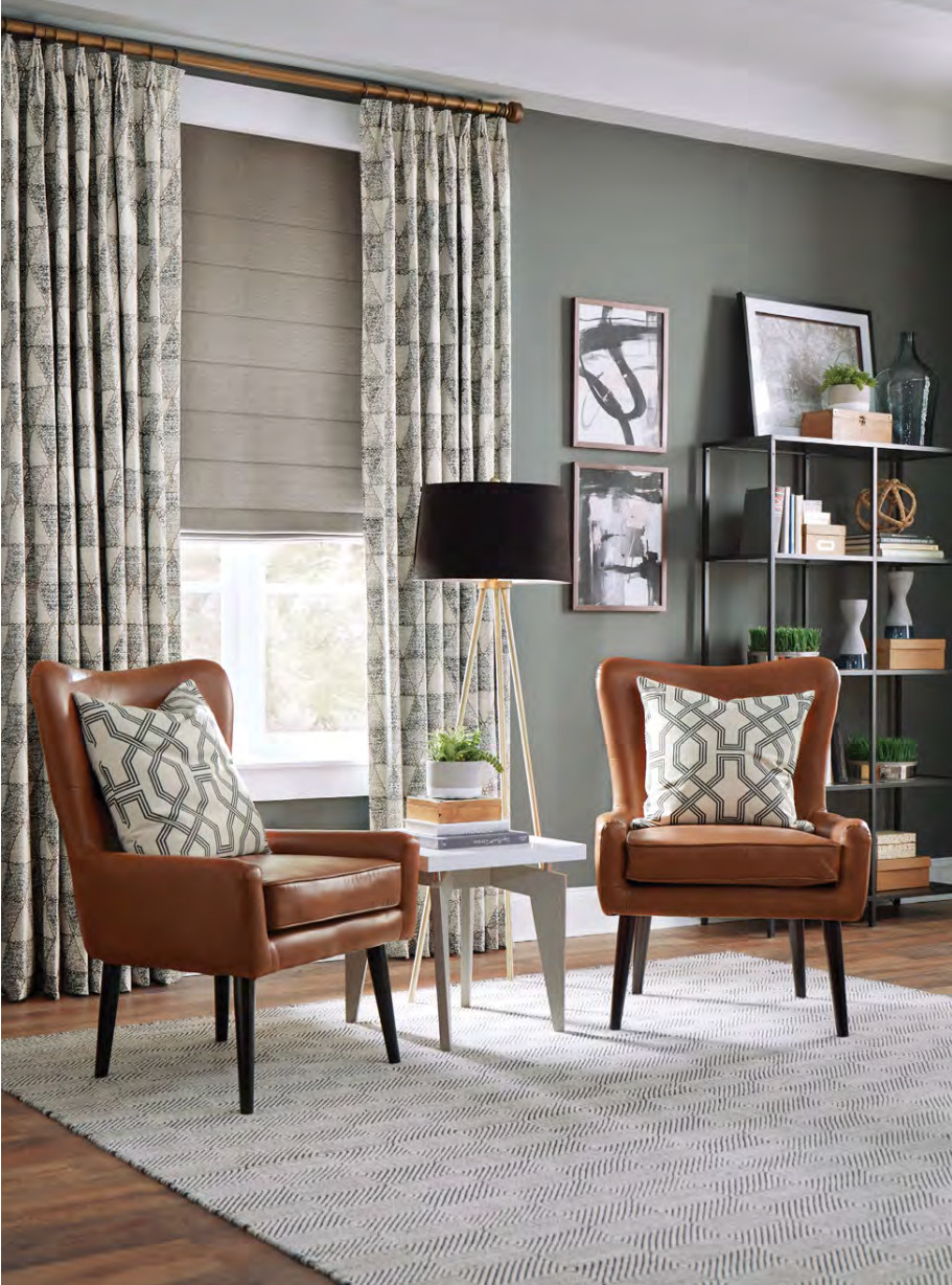 Two brown leather chairs in a living room with patterned rug, curtains, and green wall.