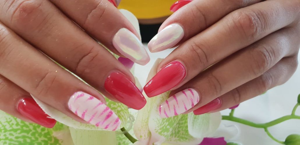 Eine Nahaufnahme der Nägel einer Frau mit einer Blume im Hintergrund.