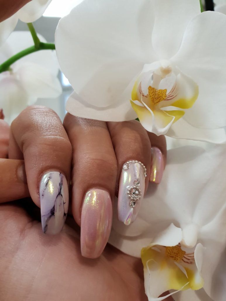 Eine Nahaufnahme der Nägel einer Frau mit einer Blume im Hintergrund