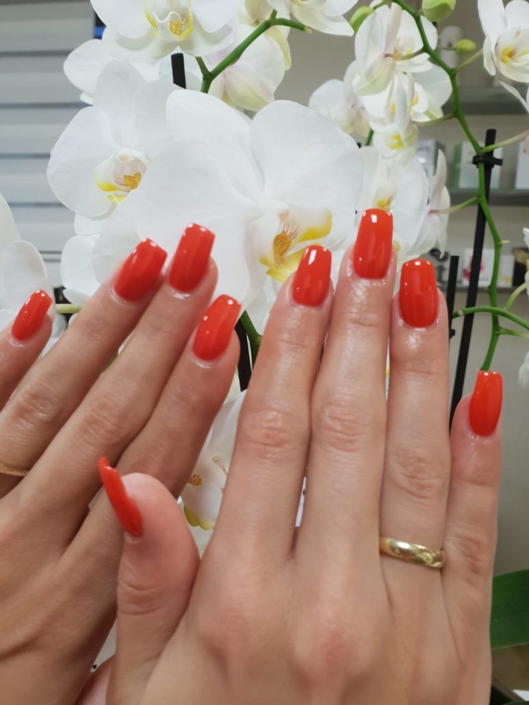 Eine Frauenhand mit roten Nägeln und einem goldenen Ring