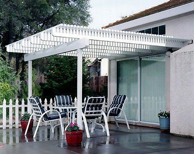 Patio with white pergola, table, chairs, and sliding glass door.