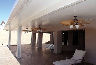 Covered patio with ceiling fans, columns, and a lounge chair.
