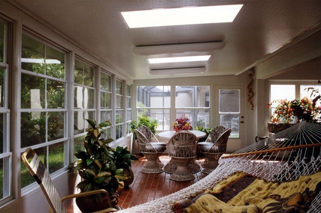 Sunroom with windows, skylights, wicker furniture, and a hammock.