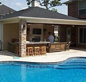 Backyard patio with pool, bar, TV, and seating under a dark roof.