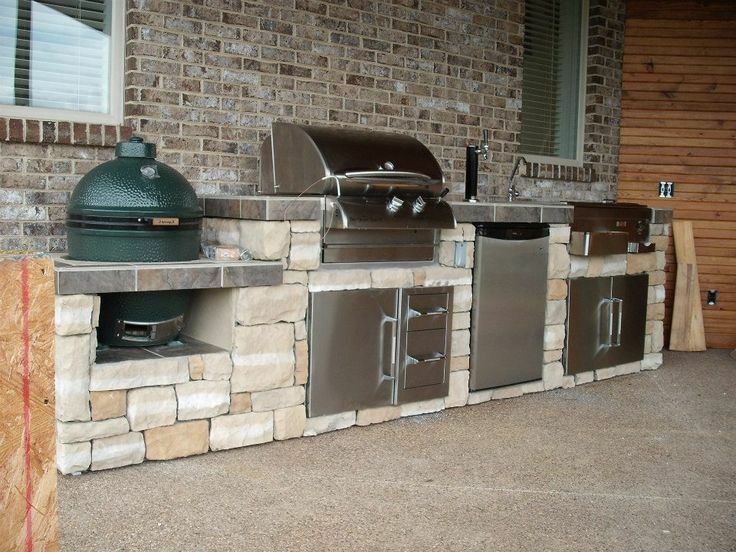 Outdoor kitchen with stone base, stainless steel appliances, and Big Green Egg.