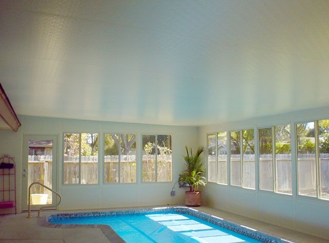 Indoor swimming pool with blue water and sunlight streaming through windows.
