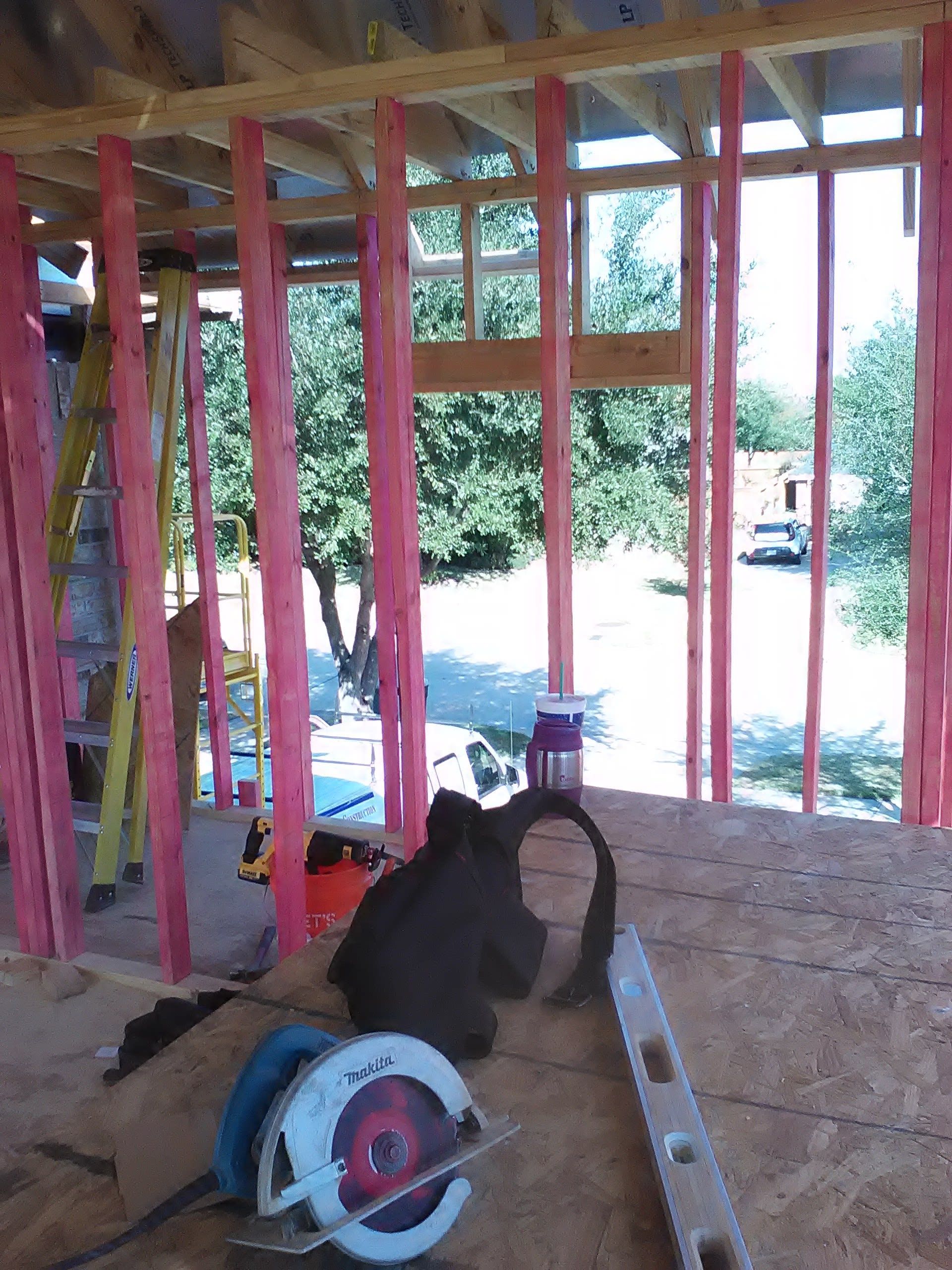 Construction site interior with pink-treated lumber framing a window, circular saw and tools on the floor