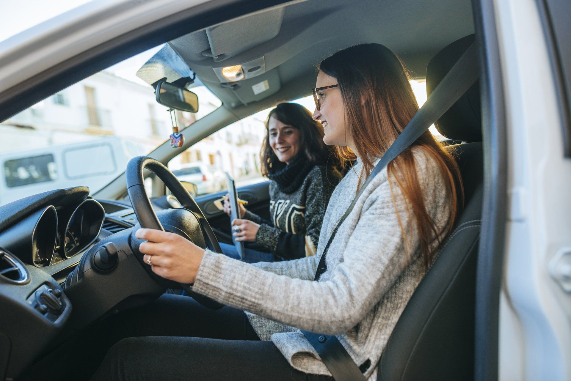 Teen in a car with a driving instructor for a behind the wheel driving lesson.