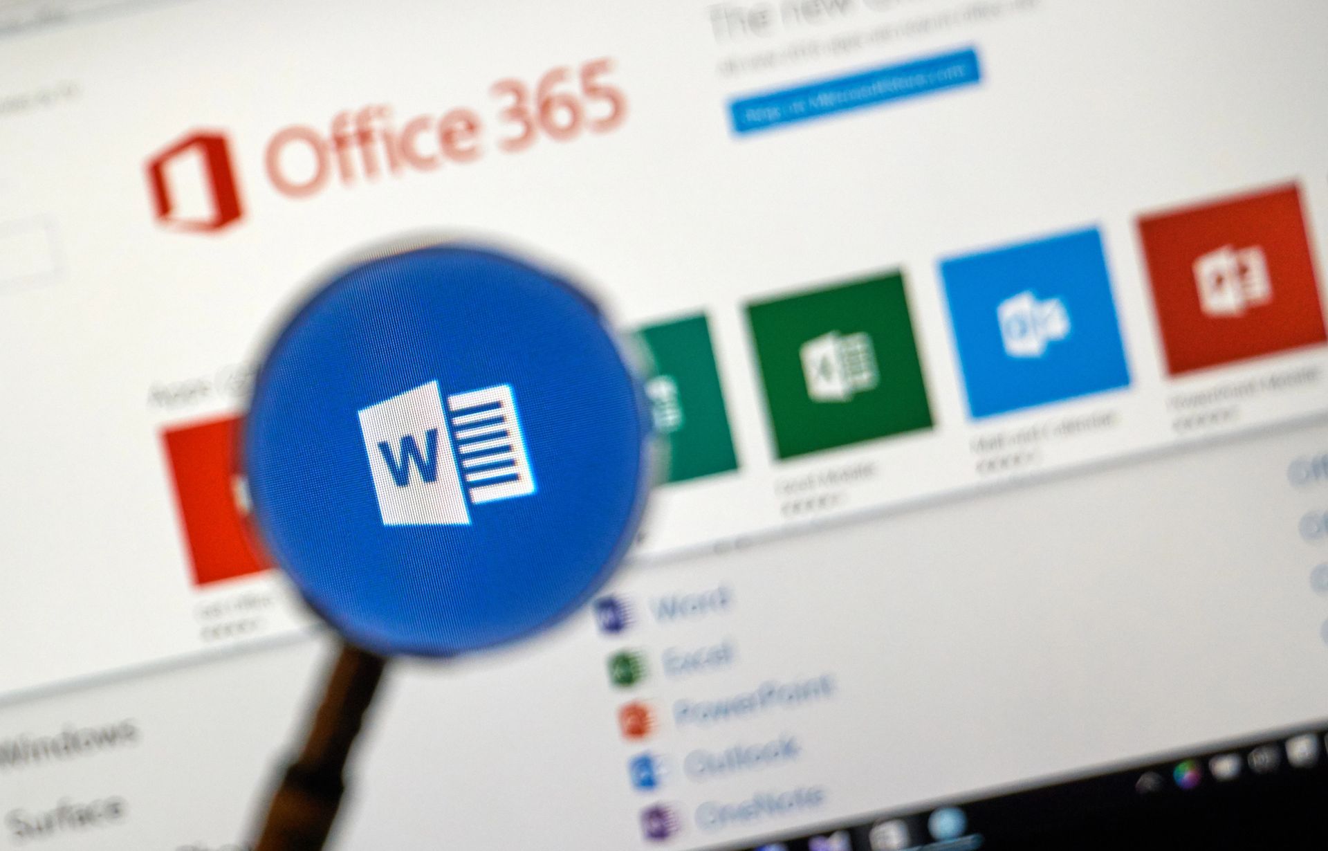 Una lupa enfoca el icono de Microsoft Word en la pantalla de un ordenador que muestra el panel de control de Office 365.