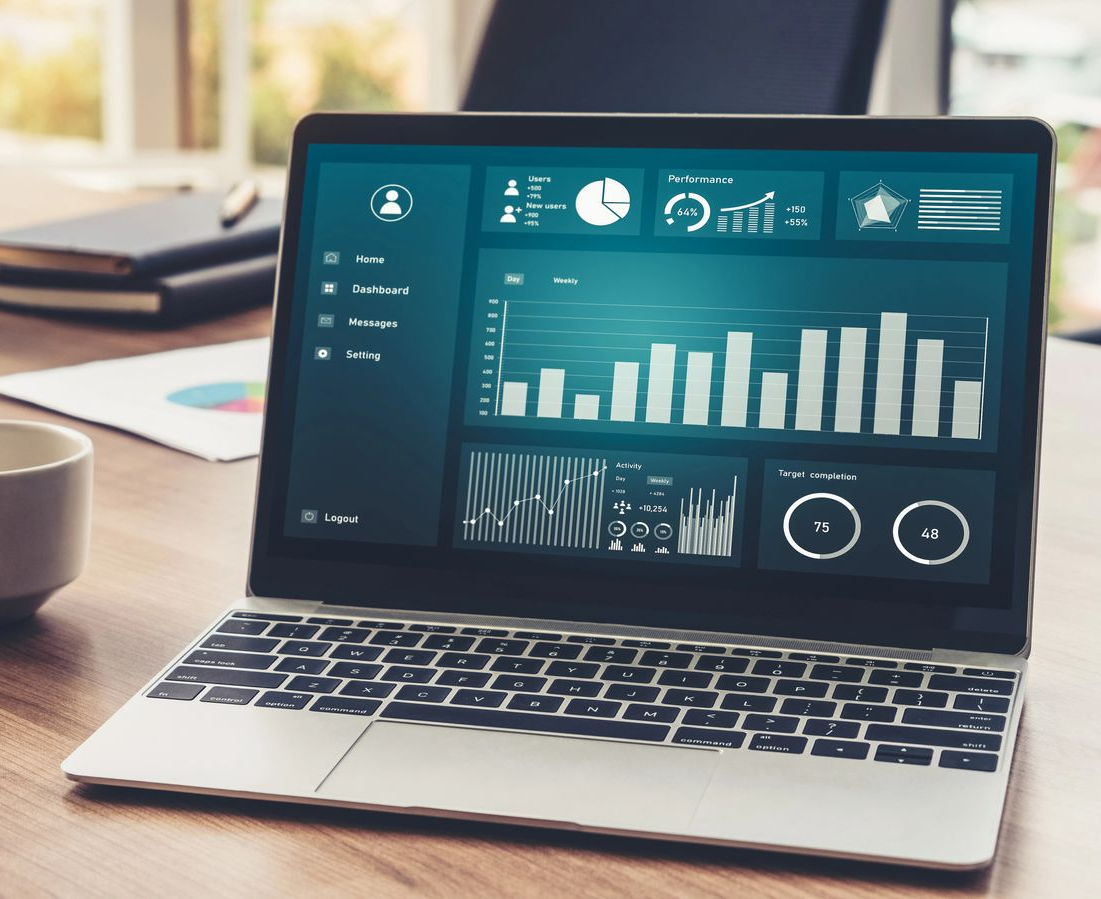 Un ordenador portátil sobre un escritorio de madera muestra un panel de control digital con diversos gráficos