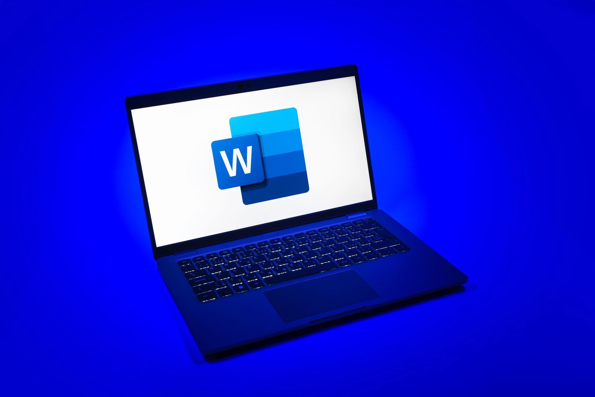Sobre un fondo azul liso, se ve un ordenador portátil con el logotipo de Microsoft Word en su pantalla blanca.