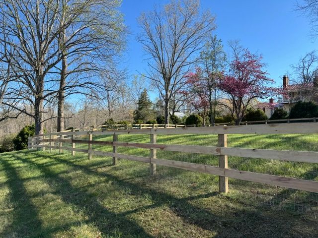 A wooden fence surrounds a grassy field with trees in the background — Scottsville, Va — Pbr Grounds Llc