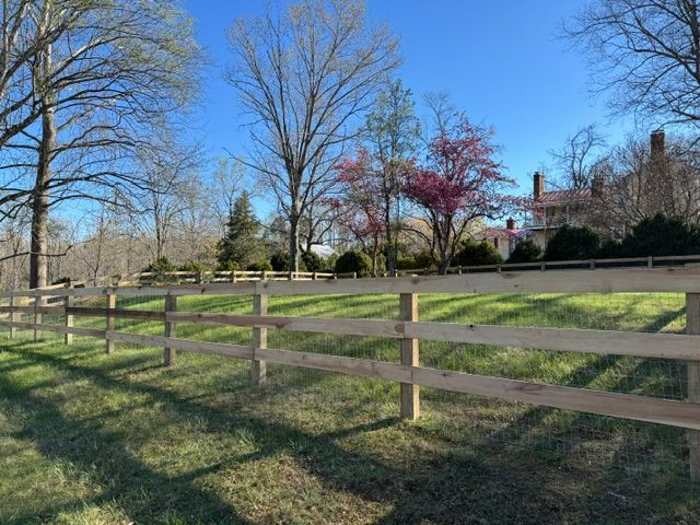 A wooden fence surrounds a grassy field with trees in the background — Scottsville, Va — Pbr Grounds Llc