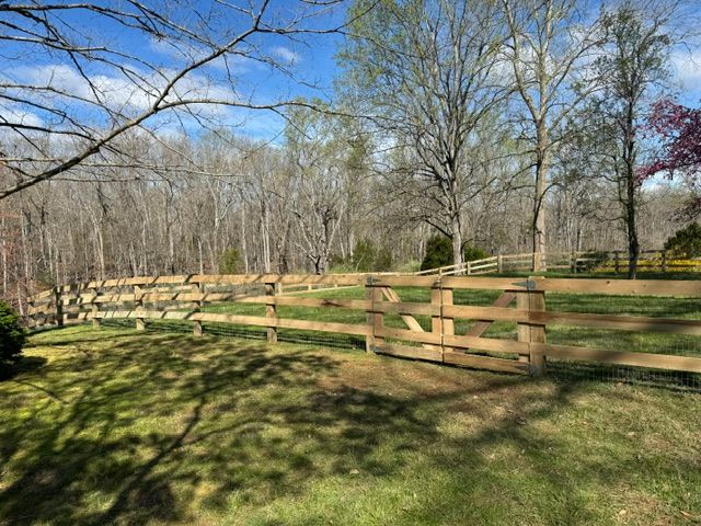 A wooden fence surrounds a grassy field with trees in the background — Scottsville, Va — Pbr Grounds Llc
