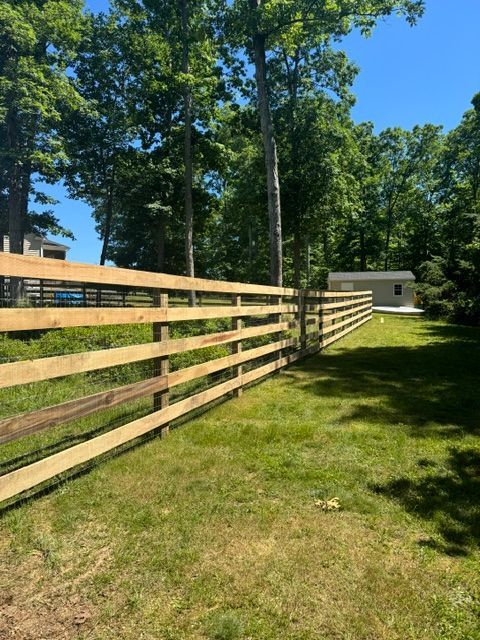 A wooden fence surrounds a lush green field with trees in the background — Scottsville, Va — Pbr Grounds Llc