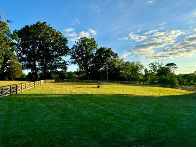 A fence surrounds a lush green field with trees in the background | Scottsville, VA | PBR Grounds LLC