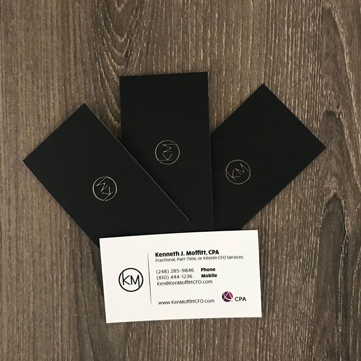 Three business cards are stacked on top of each other on a wooden table