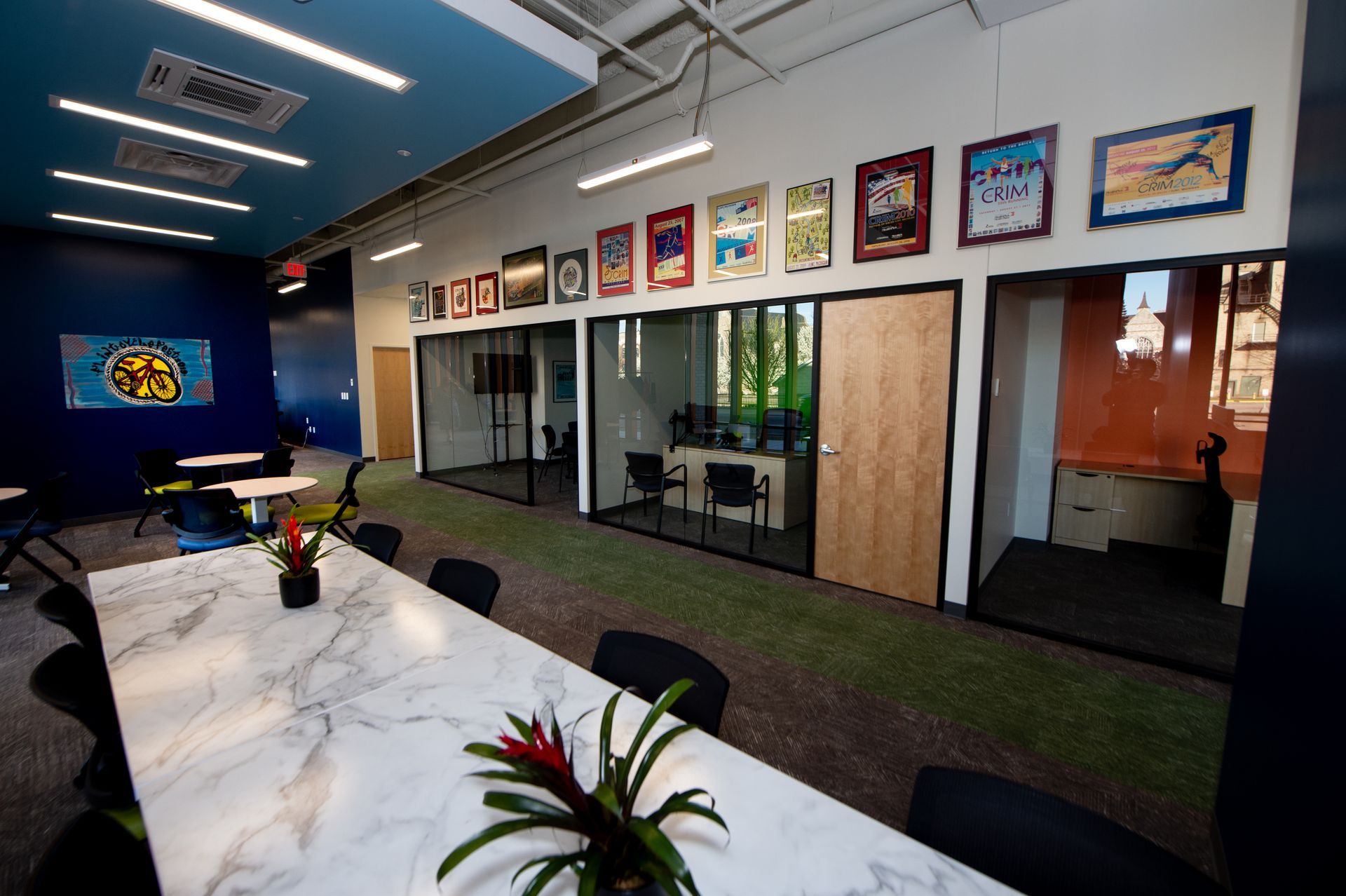 A conference room with a table and chairs and a row of pictures on the wall.