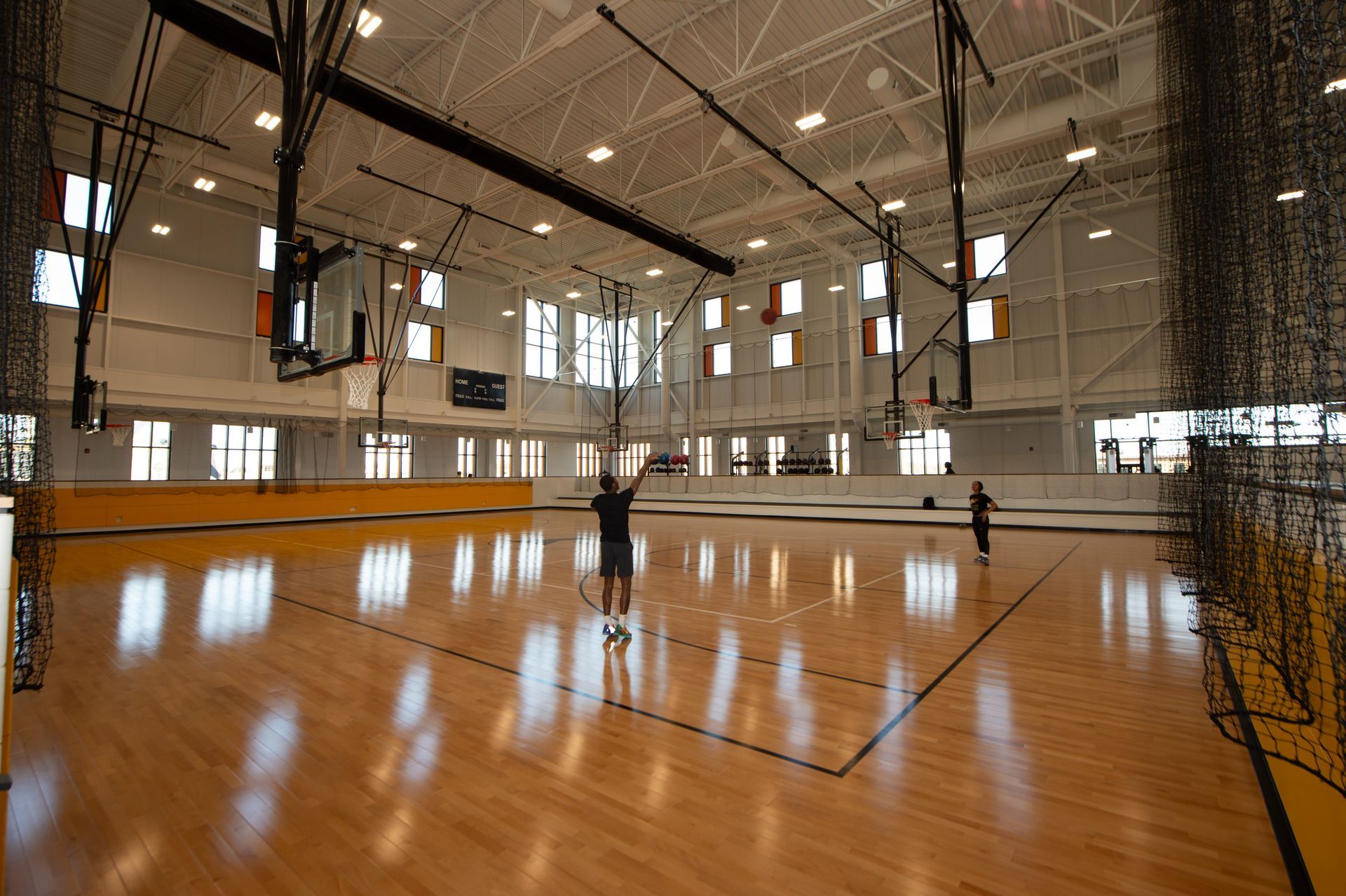 A man is playing basketball in a large gym.