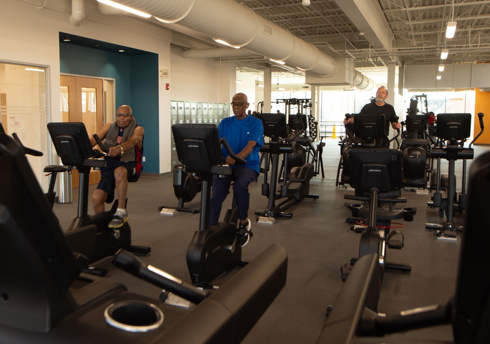 A group of men are riding exercise bikes in a gym.